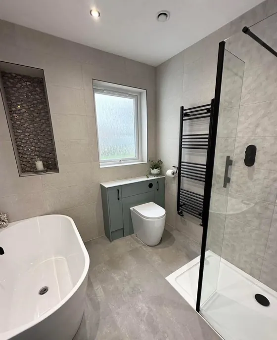 Bathroom with a freestanding bath, mosaic tiled niche, black towel rail and a sage green vanity