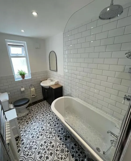 Traditional bathroom with white metro tiling, a patterned floor and a roll top style bath