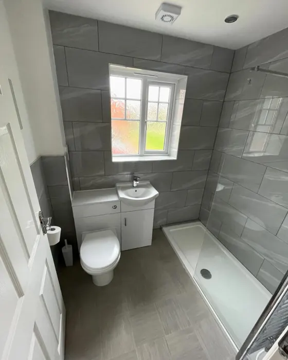Compact shower room with a low profile shower tray, white basin and toilet