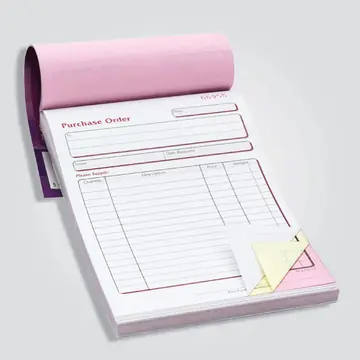 An NCR purchase order pad opened to show the white top sheet with pink and yellow duplicate sheets beneath.