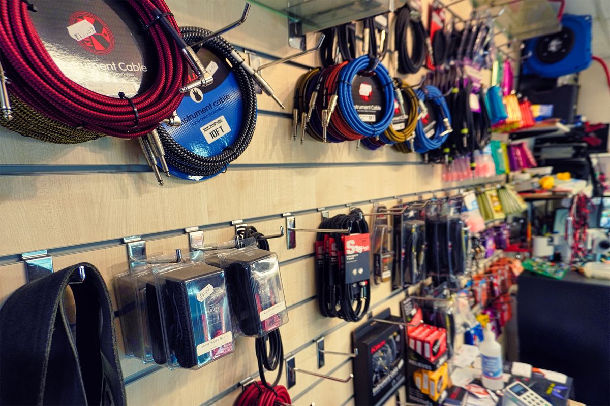 A shop wall of coiled instrument cables in red, blue and multicolour braid