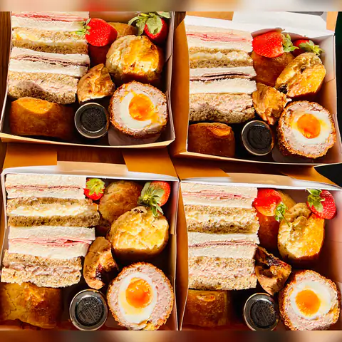 Individual afternoon tea boxes with finger sandwiches, quiche and a scotch egg