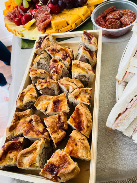 A buffet tray of golden pastries beside a platter of sandwiches