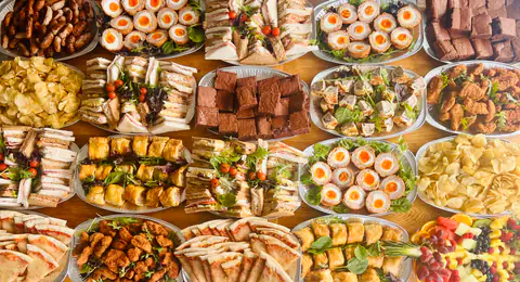 Overhead view of buffet platters: sandwiches, brownies, scotch eggs and skewers