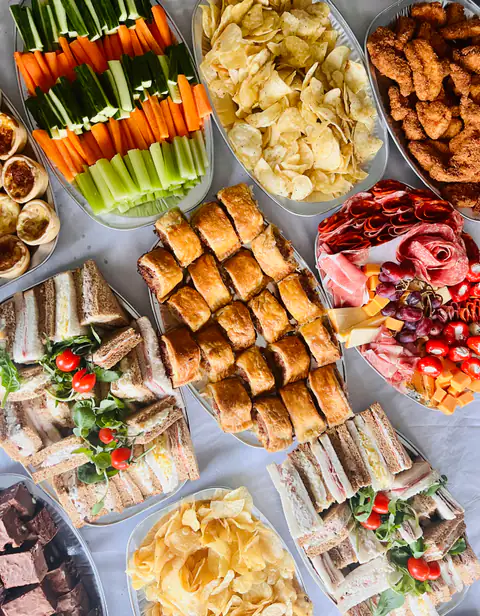 A full buffet spread of sandwiches, crudités, crisps, cured meats and cheese