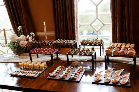 Canapés on black risers beside a lit candle in a bay-windowed room
