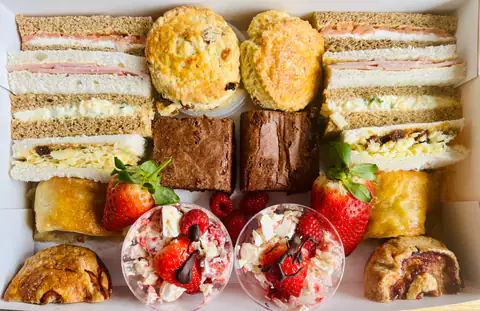 Strawberry desserts and quiche beside finger sandwiches on a tea table