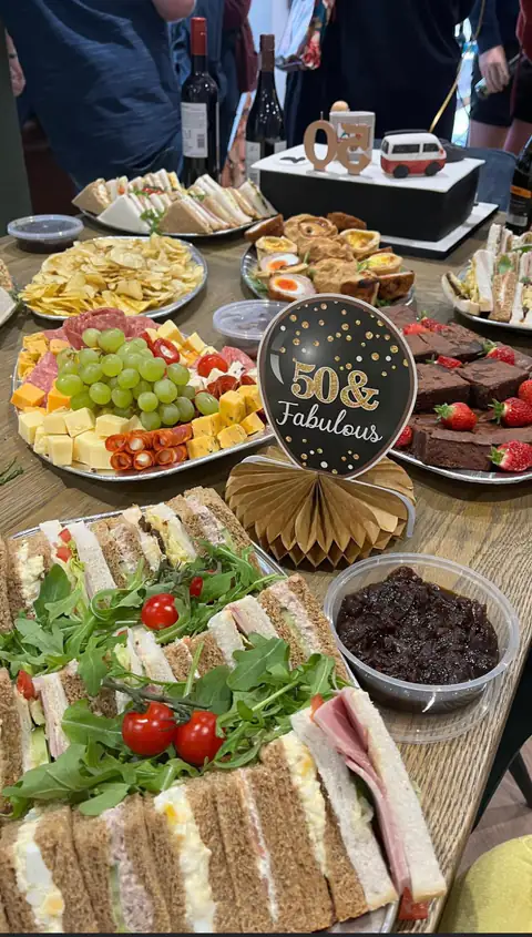 A birthday grazing table with a 50 and Fabulous sign, cheese, grapes and cured meats