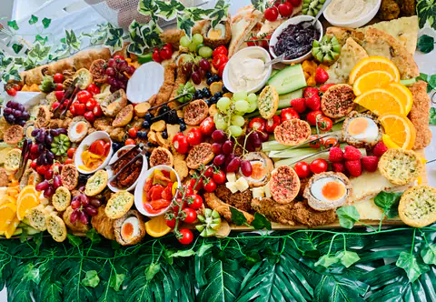 A grazing table stretching down a beamed barn, styled with foliage and loaded with sharing food