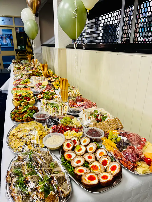 A Westwoods graze table running the full length of a function room, loaded end to end with cured meats, scotch eggs, cheeses and fruit