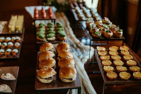 Mini burger sliders on skewers beside avocado canapés