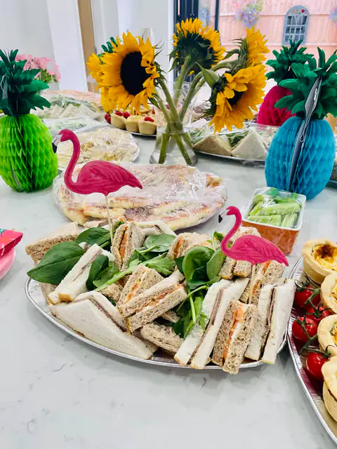 A summer party table with sandwiches, quiche and flamingo decorations