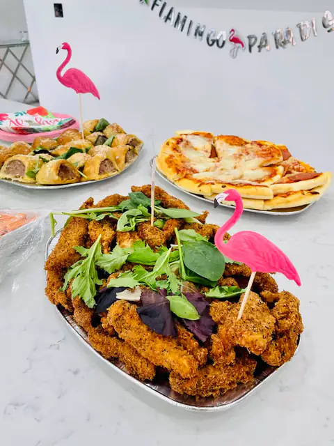 Chicken goujons and pizza on a party table with tropical decorations
