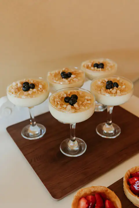 Possets with crumble topping and blueberries on a dark wooden table