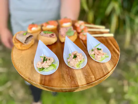 Prawn cocktail spoons and canapés arranged on a round wooden board