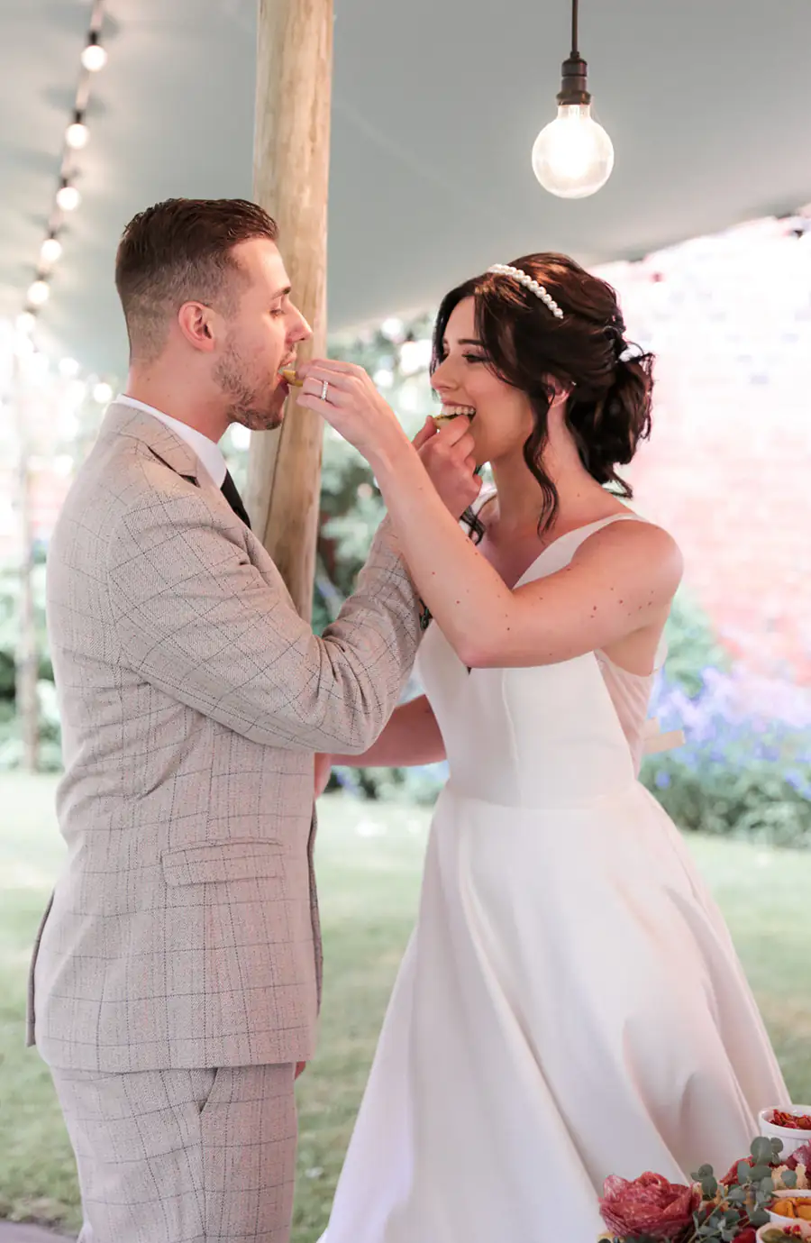 A bride and groom feeding each other from a Westwoods grazing board on their wedding day