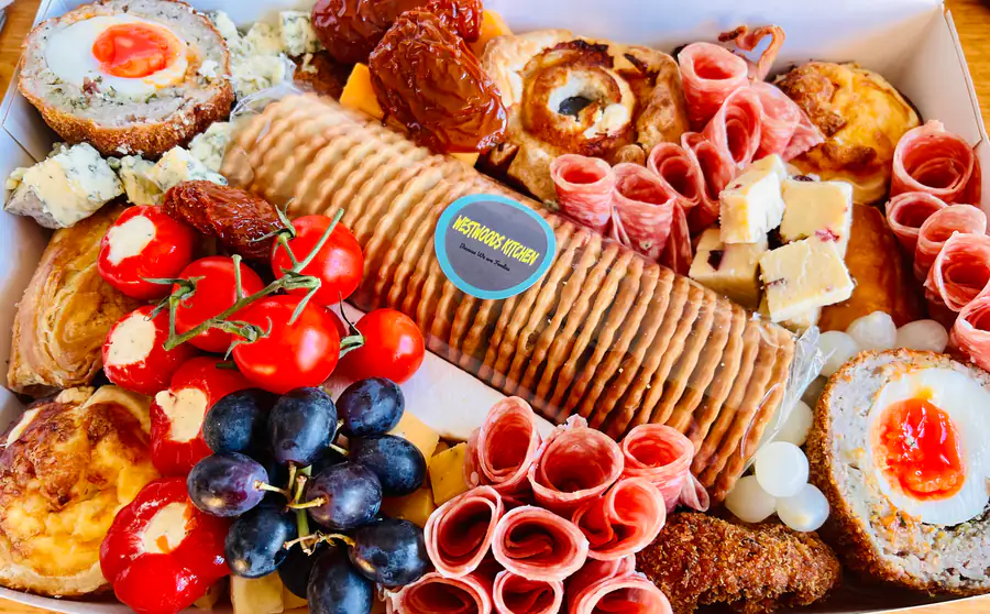 A Westwoods Kitchen branded cracker board with chorizo roses, grapes and cherry tomatoes