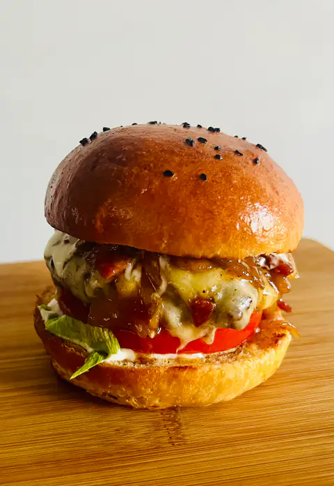 A homemade burger with melted cheese and caramelised onions in a brioche bun